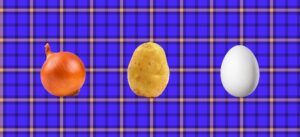 En løg, en kartoffel og et æg placeret side om side på et blåt ternet baggrundsmønster