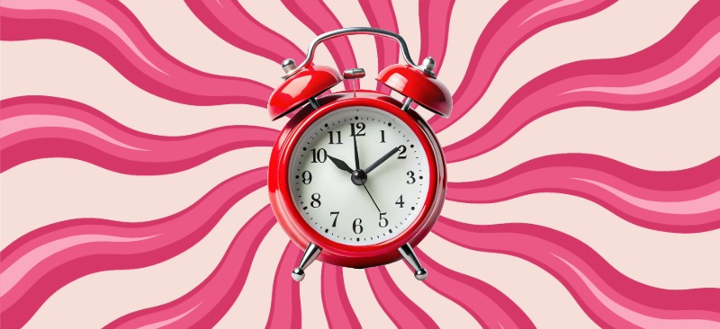 Rød retro vækkeur med hvide urskive placeret foran en baggrund med lyserøde og cremefarvede bølgemønstre.